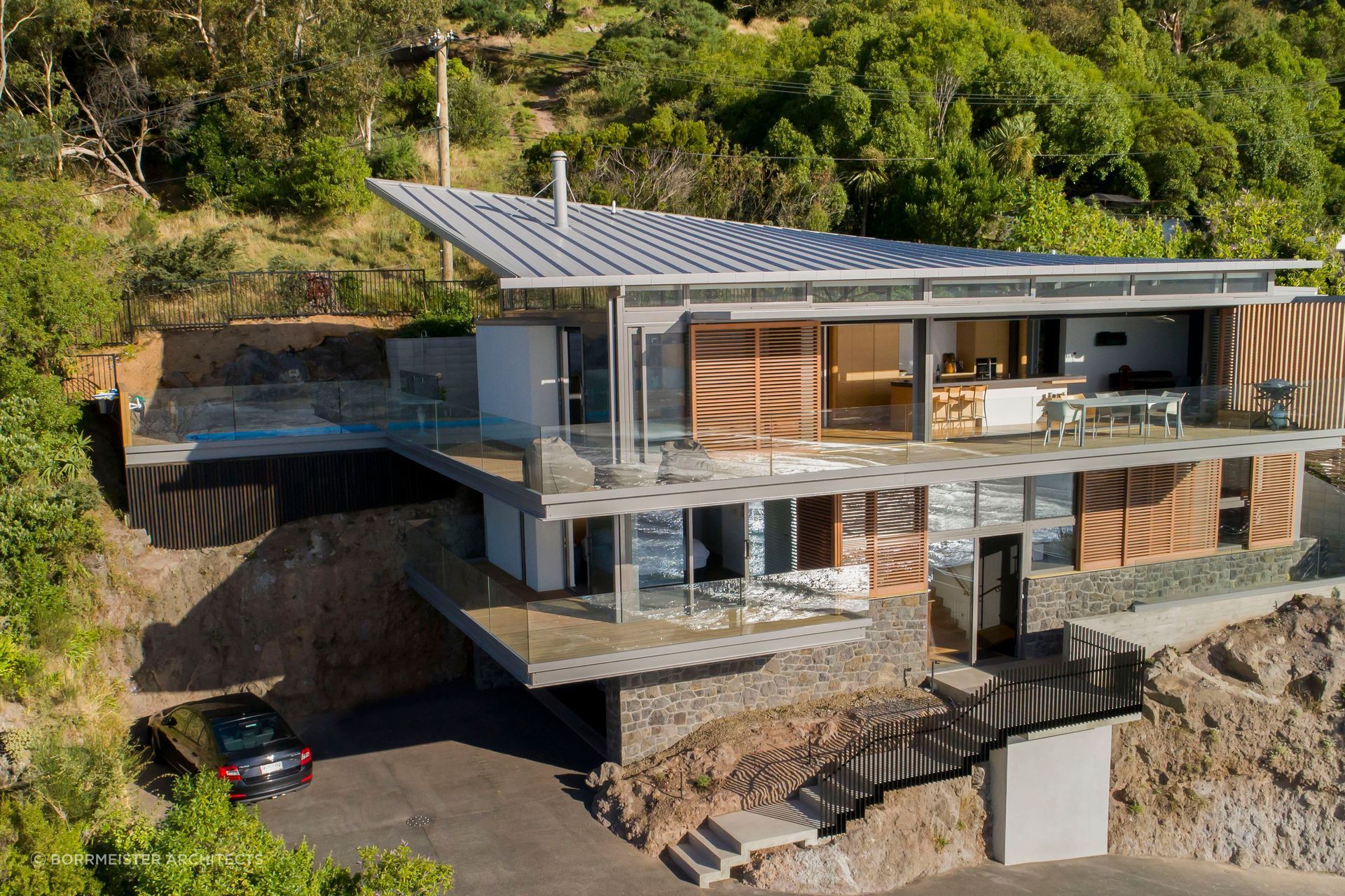 Red Rock House by Borrmeister Architects was designed to provide shelter from the prevailing winds, incorporate natural cross ventilation, solar panels, rainwater retention tanks and an ultra-low emission logburner.