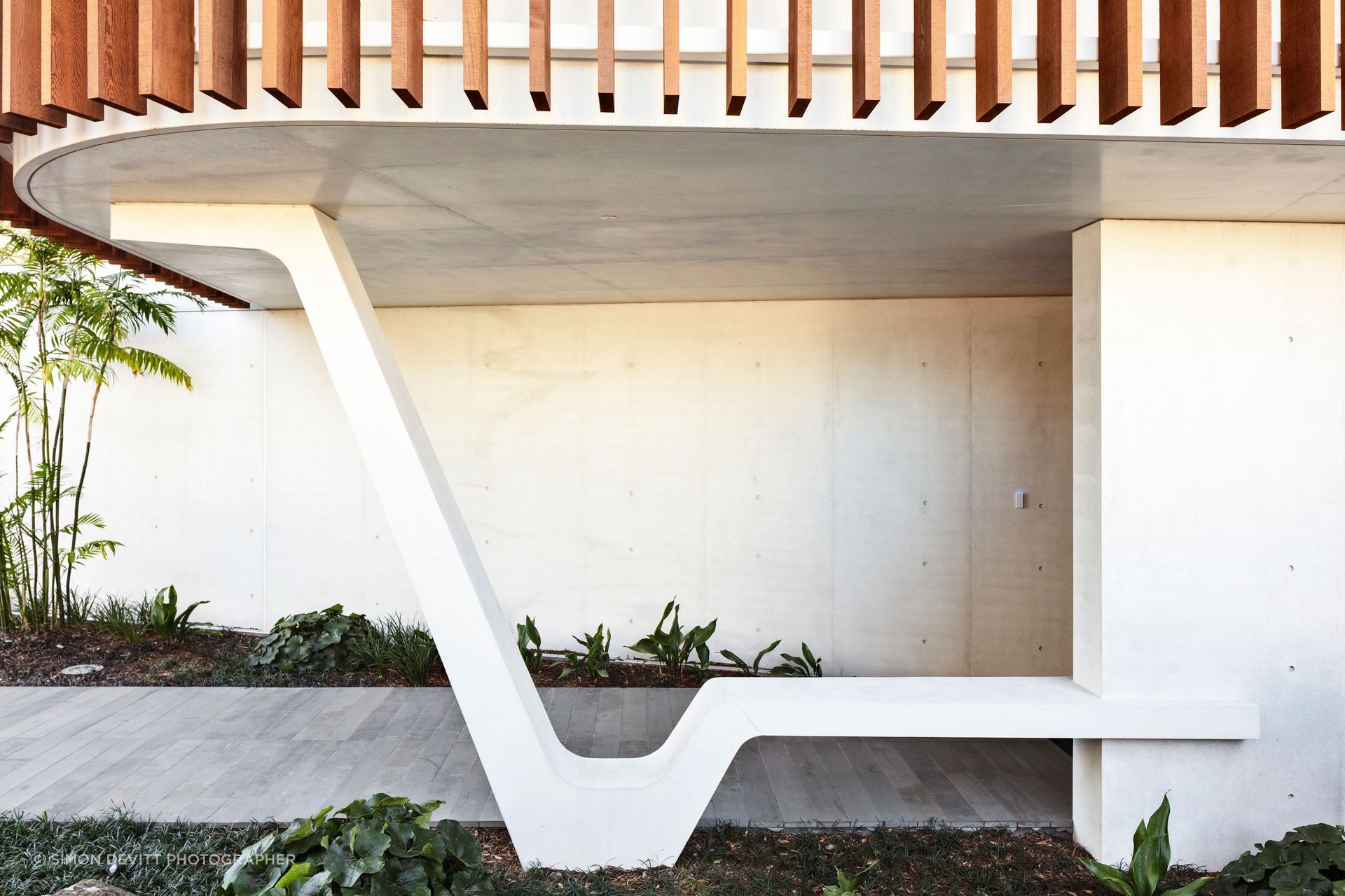 A striking sculptural element in white concrete provides a perfectly serene spot to sit and take off your shoes at the entrance of Clifftops house.