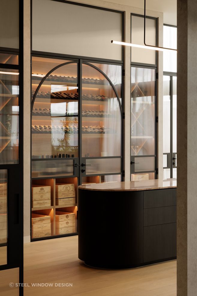 A wine cellar framed in bold black steel and glazing.