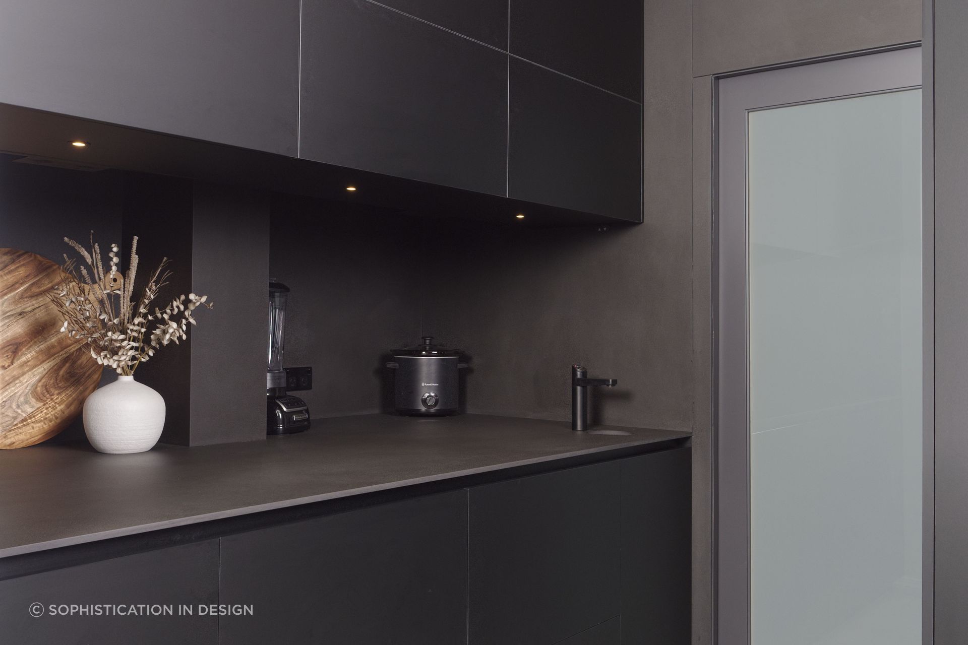 Appliances disappear within the dark spashback and bench.