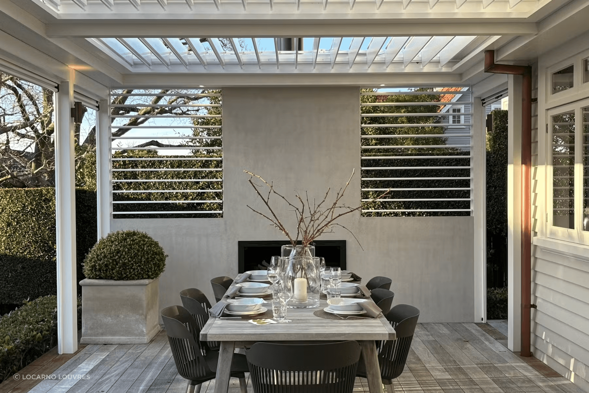 The pergola incorporates four motorised panels of The super fine profile RLS200 louvres can be closed to provide shelter or opened to maximise light in the adjacent kitchen/living rooms. Two panels of manually adjustable RL130 screens add the finishing touch on either side of the plastered chimney.