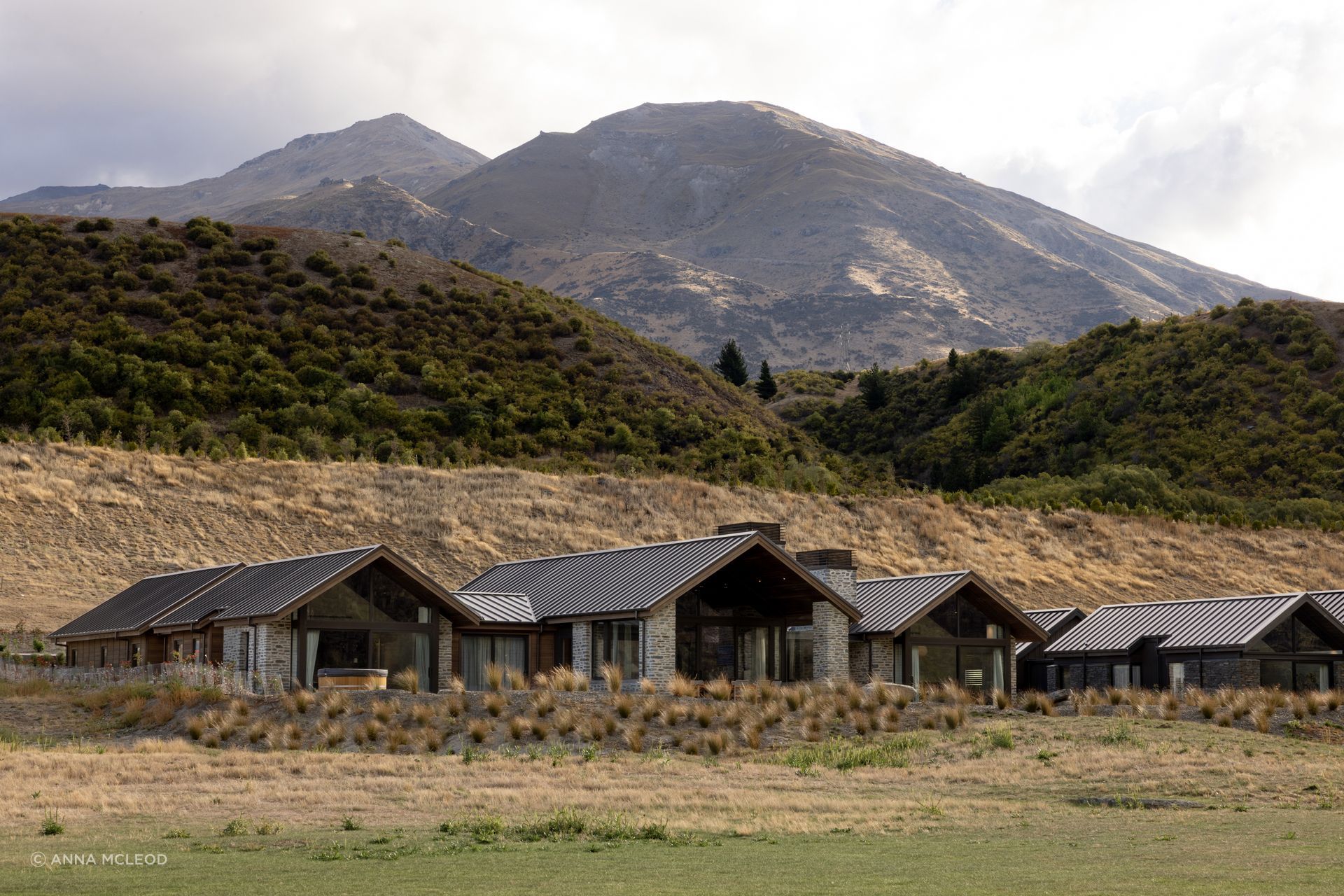 Gibbston Valley House by Condon Scott Architects reads as a series of schist-clad gables set low in the landscape, echoing the colours and contours of the surrounding Gibbston Valley hills | Photography by Anna McLeod