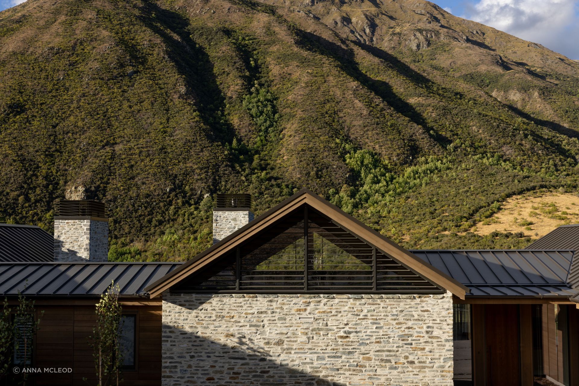 At Gibbston Valley House by Condon Scott Architects, finely laid schist walls and chimneys are paired with timber and metal roofing to create a refined, lodge-like profile | Photography by Anna McLeod