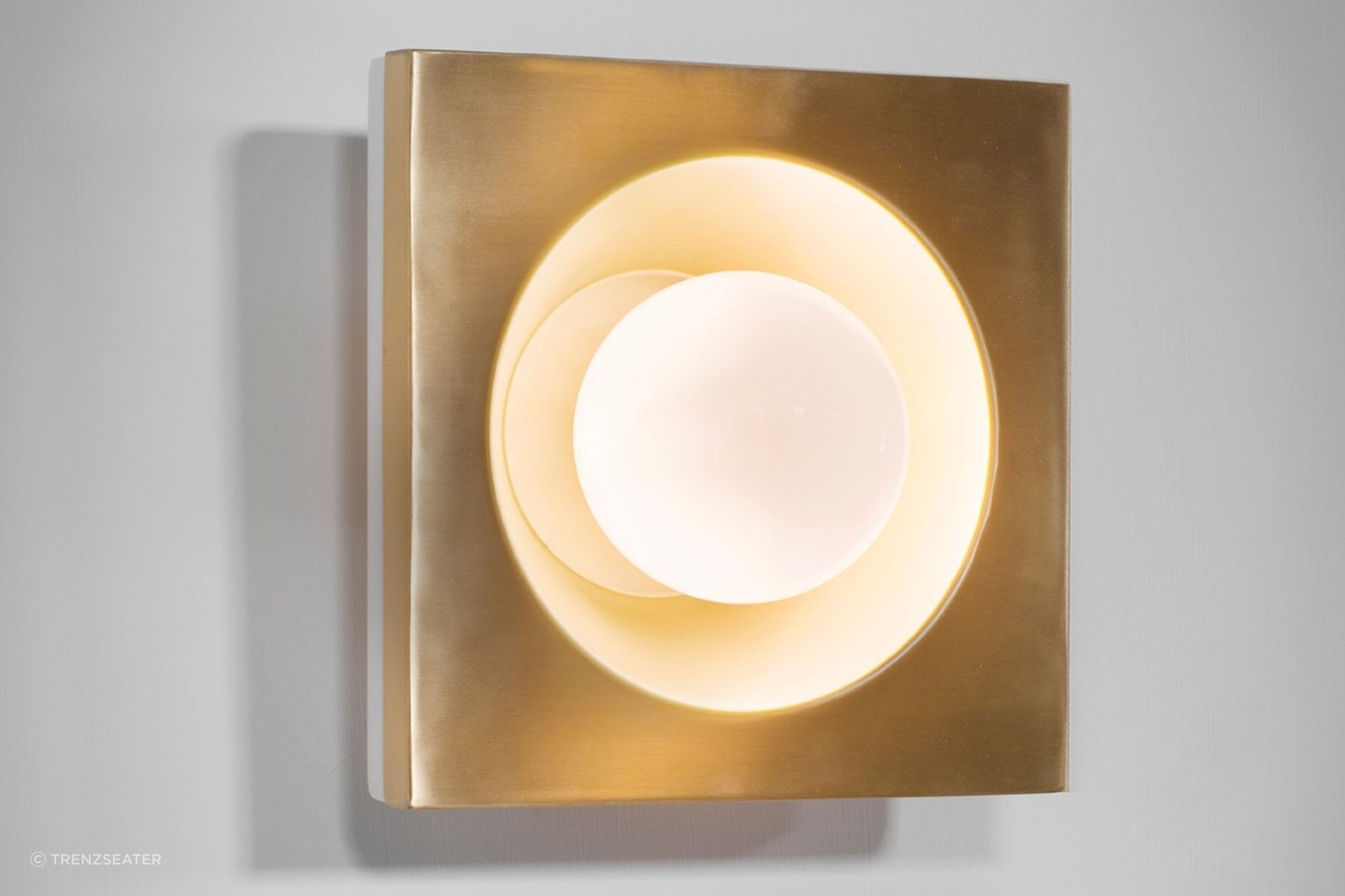 The Kins Wall Light and its warm Brass lacquered metal finish.