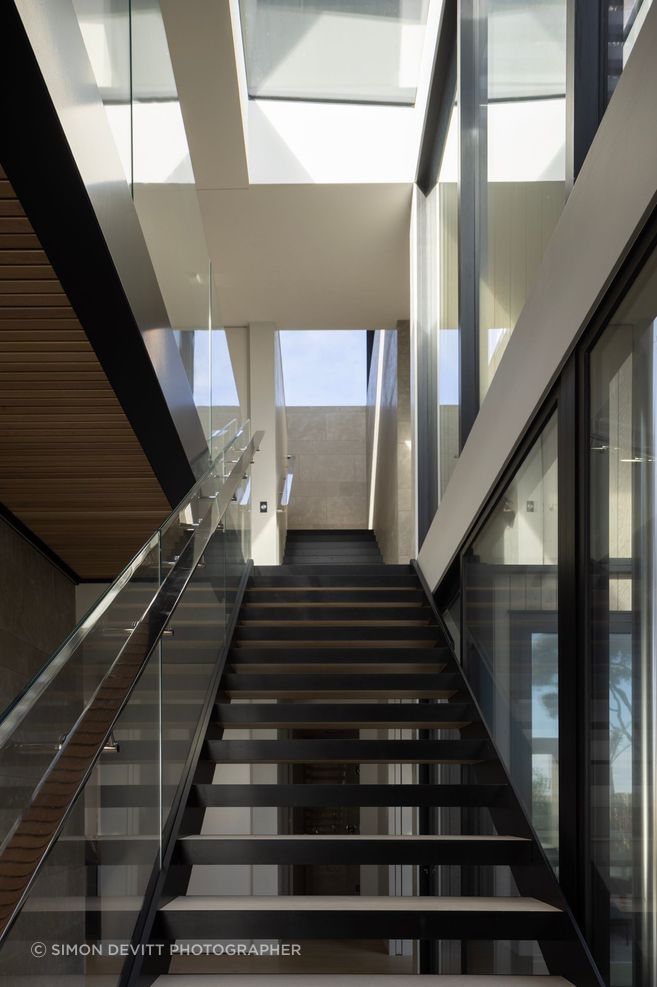 At Pohutukawa House, the journey down two sets of stairs tempts visitors down to the main living space on the bottom floor.
