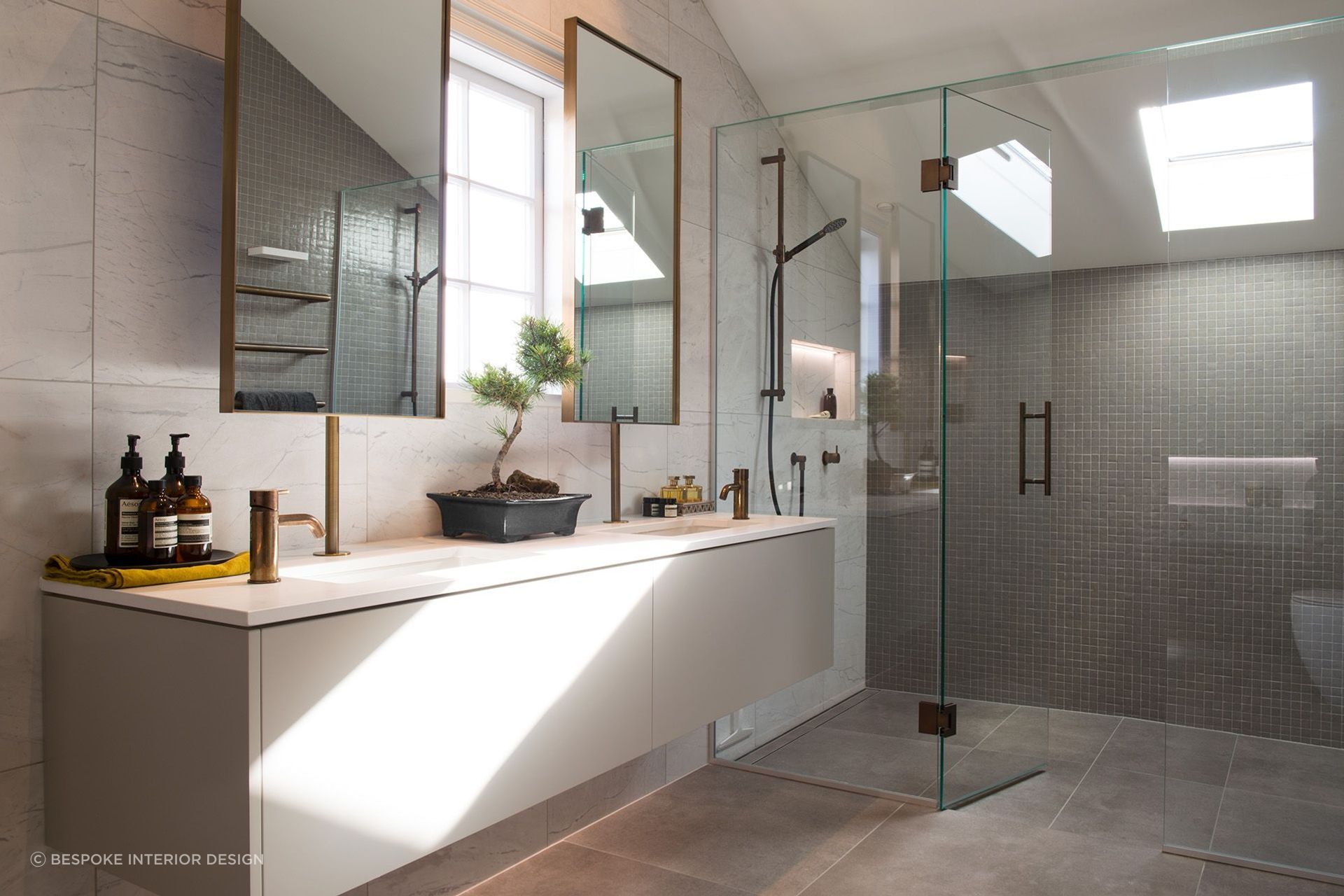 The beautiful bathroom renovation of Rangitoto House featuring vanity-mounted mirrors.