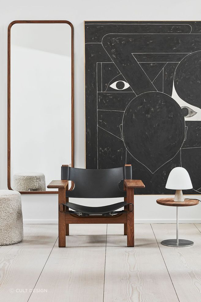 The sleek Silhouette Mirror Rectangle by Fredericia positioned behind an armchair and stool.