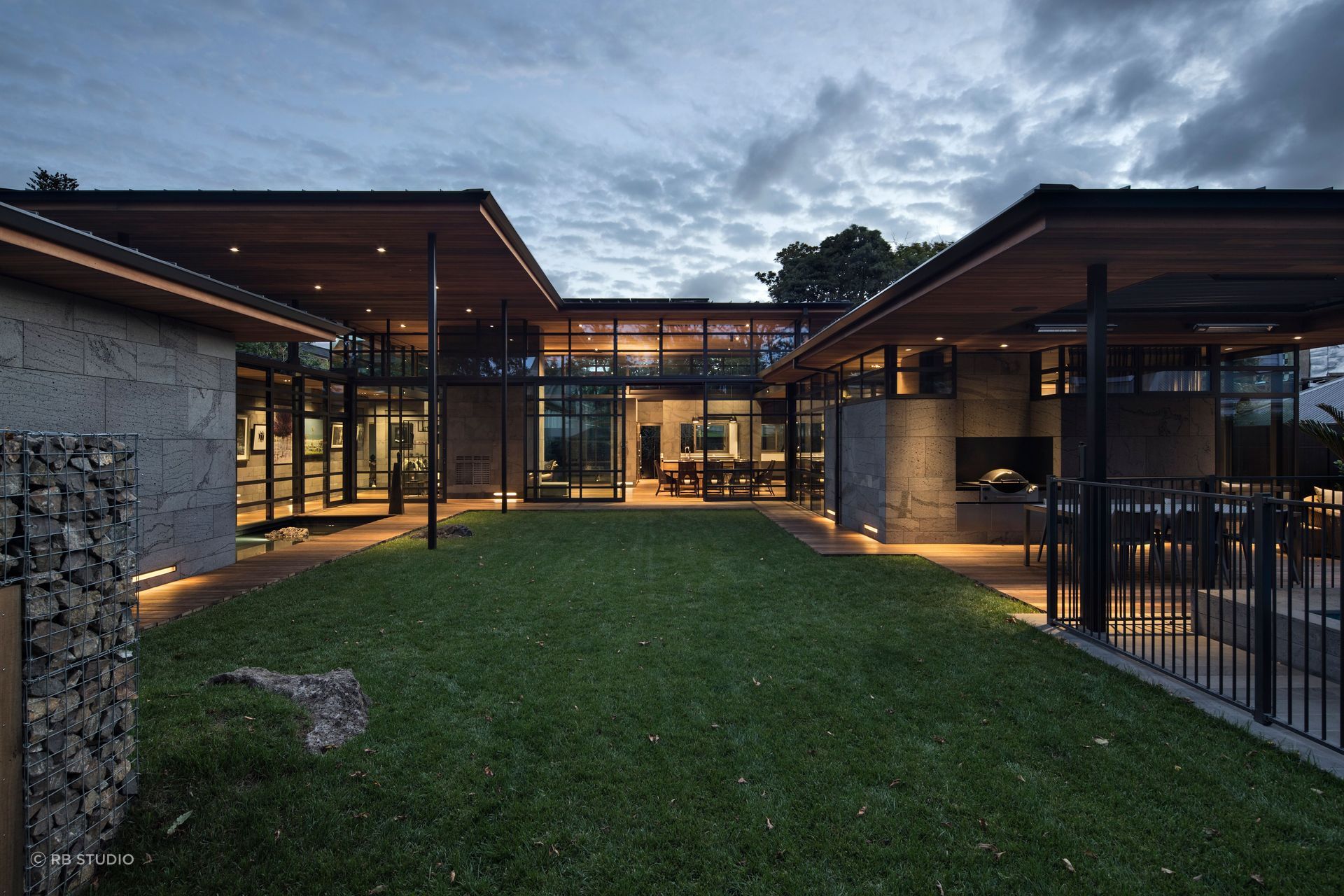 Volcano House by RB Studio wraps the central lawn with basalt-clad pavilions, where Timaru Bluestone walls, timber ceilings and glazing frame a series of intimate micro-landscapes.