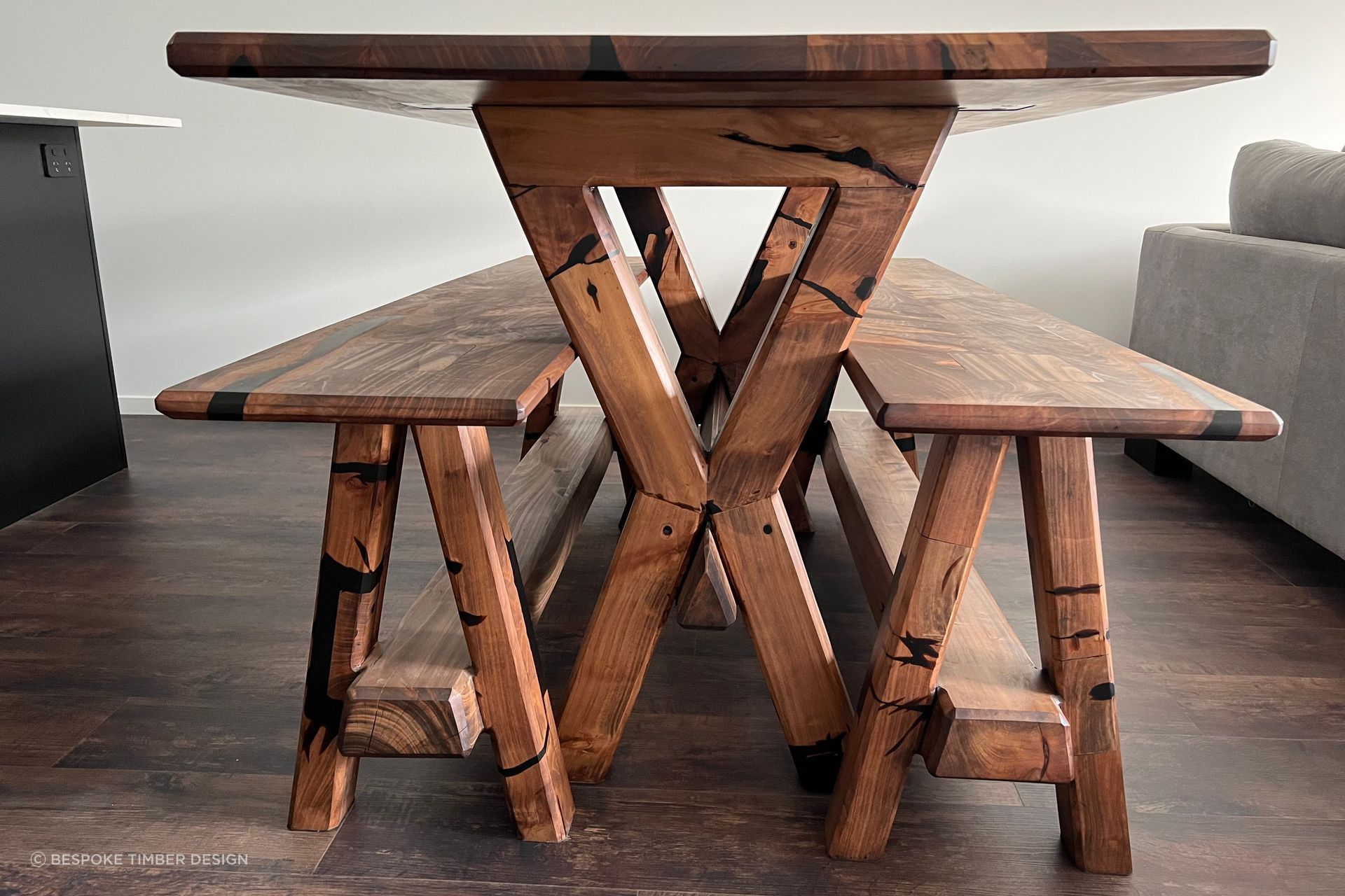 Reclaimed macrocarpa timber from an old table has been used to create a new table and accompanying bench seats that encapsulate the unique character and history of the wood. Each imperfection in the timber has been transformed into a striking feature, accentuated by stunning black epoxy infills.