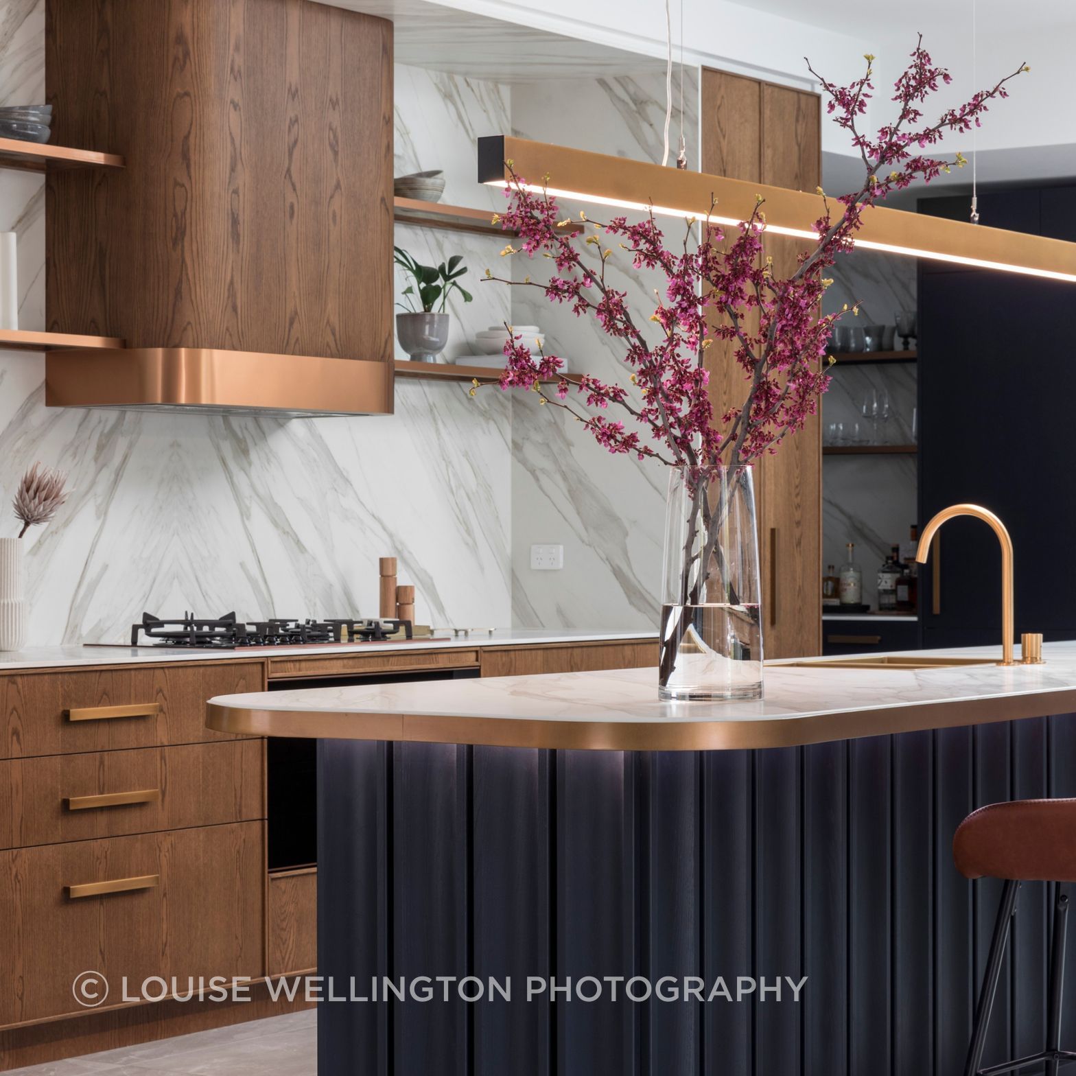 Oxford Project.  The kitchen island is a statement in Farmers Doors deep blue timber veneer, warm teak and bronze metaillic detailing