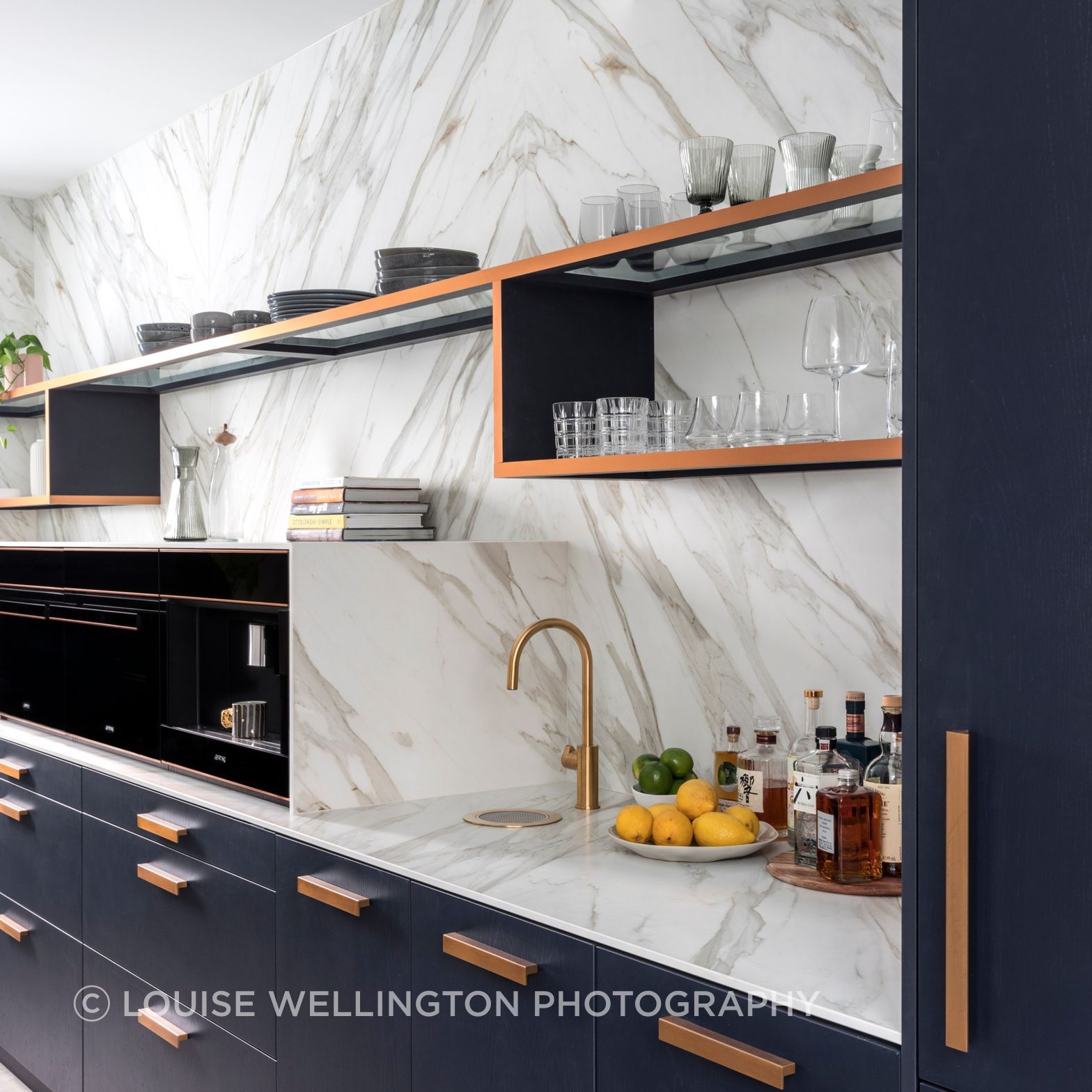 Oxford Project.  The open scullery features Neolith clad walls and benchtops, cooking and bar zone with deep blue cabinetry and bronze metallic highlights