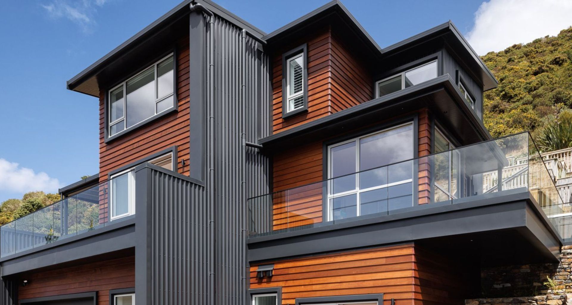 Cedar wood weatherboards juxtapose with black metal cladding, bringing an architectural flair to Tom Wilson's Ōwhiro Bay home