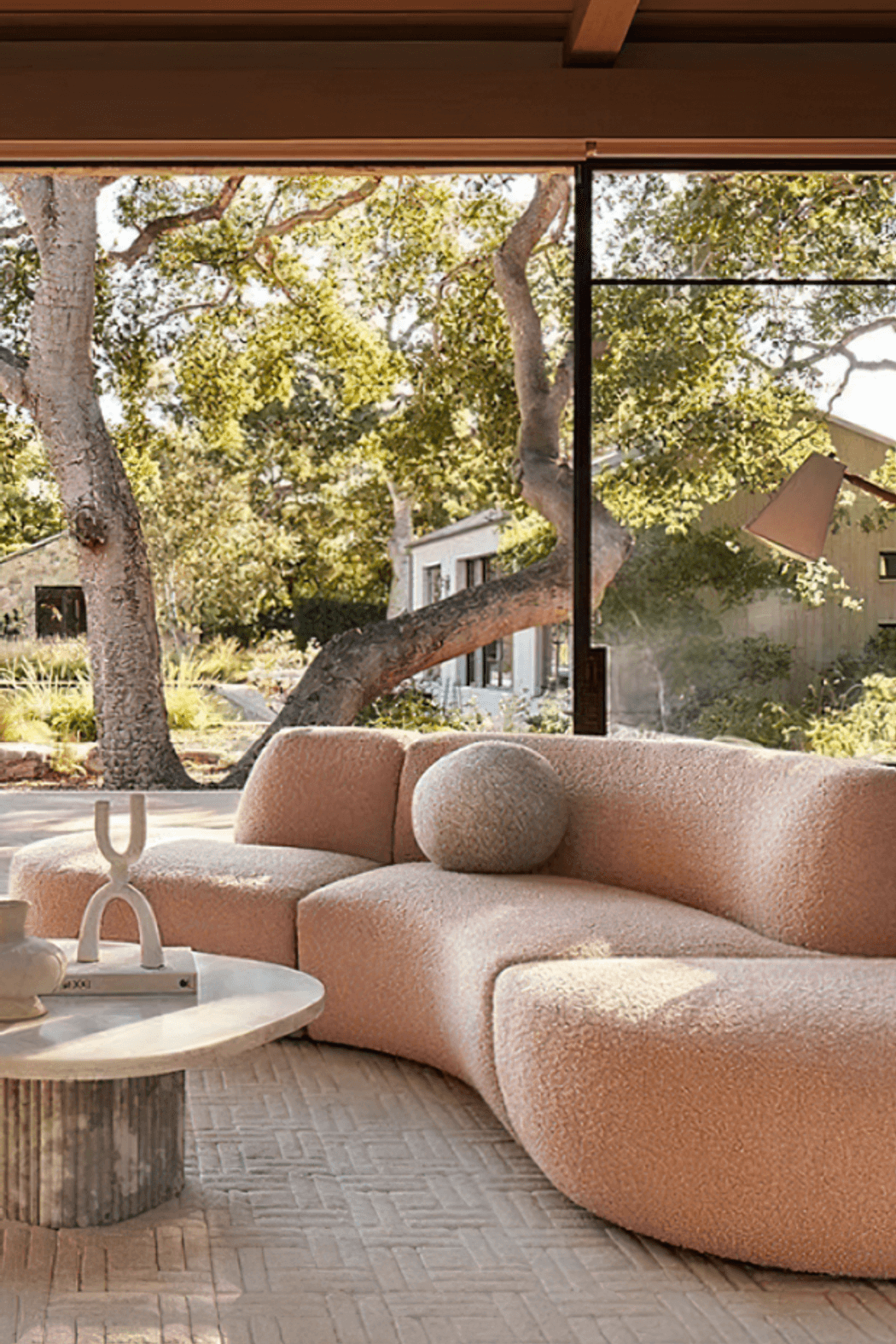 Image Credit:  Anthropologie | Curved Sofa in clay tones + biophilic design