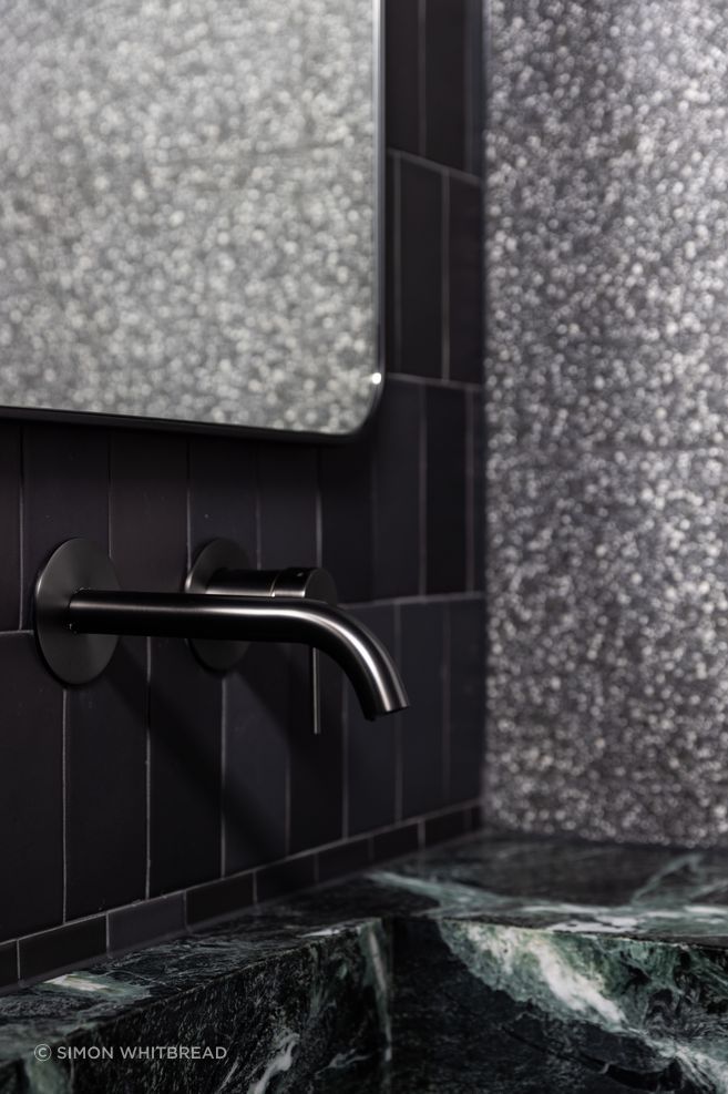 The natural green stone takes centre stage in front of the black tiles.