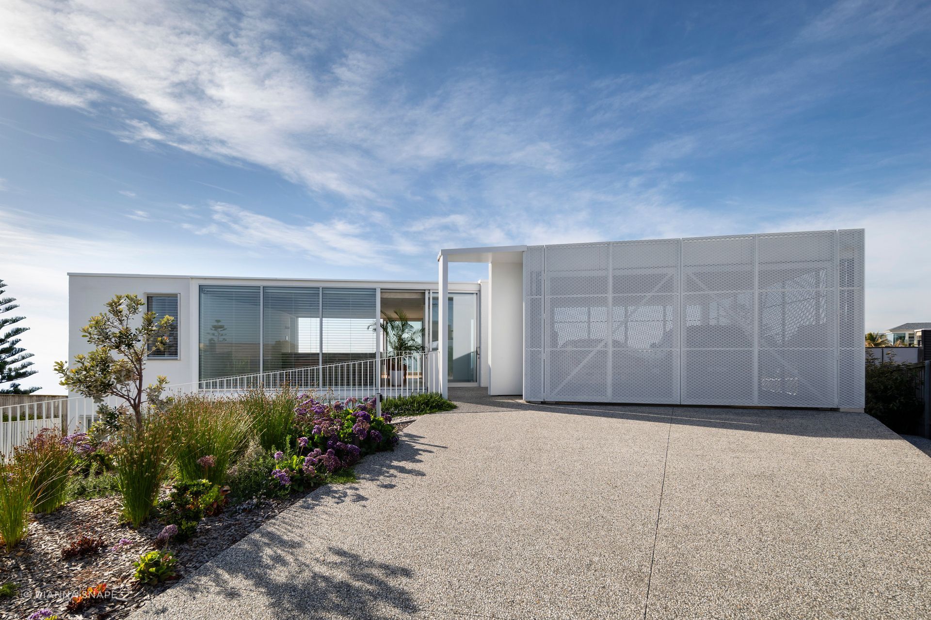 Perforated garage doors at the upper level soften the home's strong, geometric form.