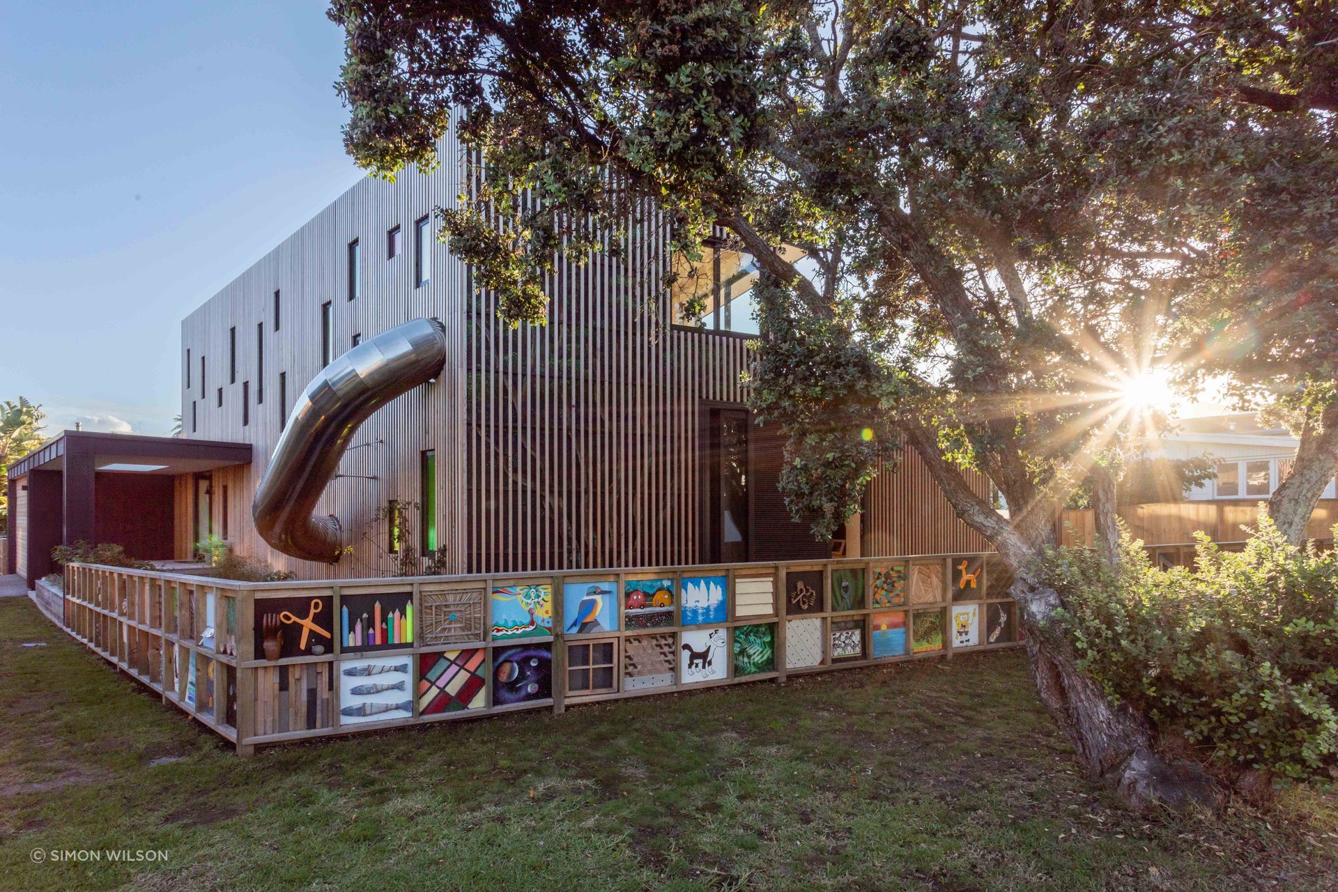 The faint outline of a pōhutukawa mural can be seen beneath the timber batten screen.