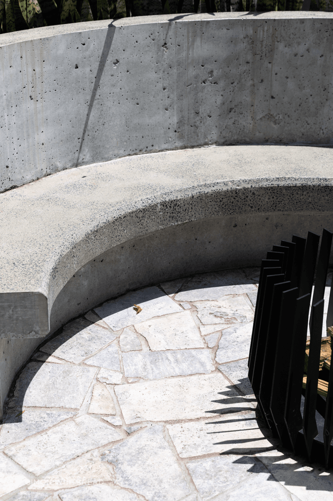 Curves, concrete and stone continue to the backyard where the family can gather around the fire pit.