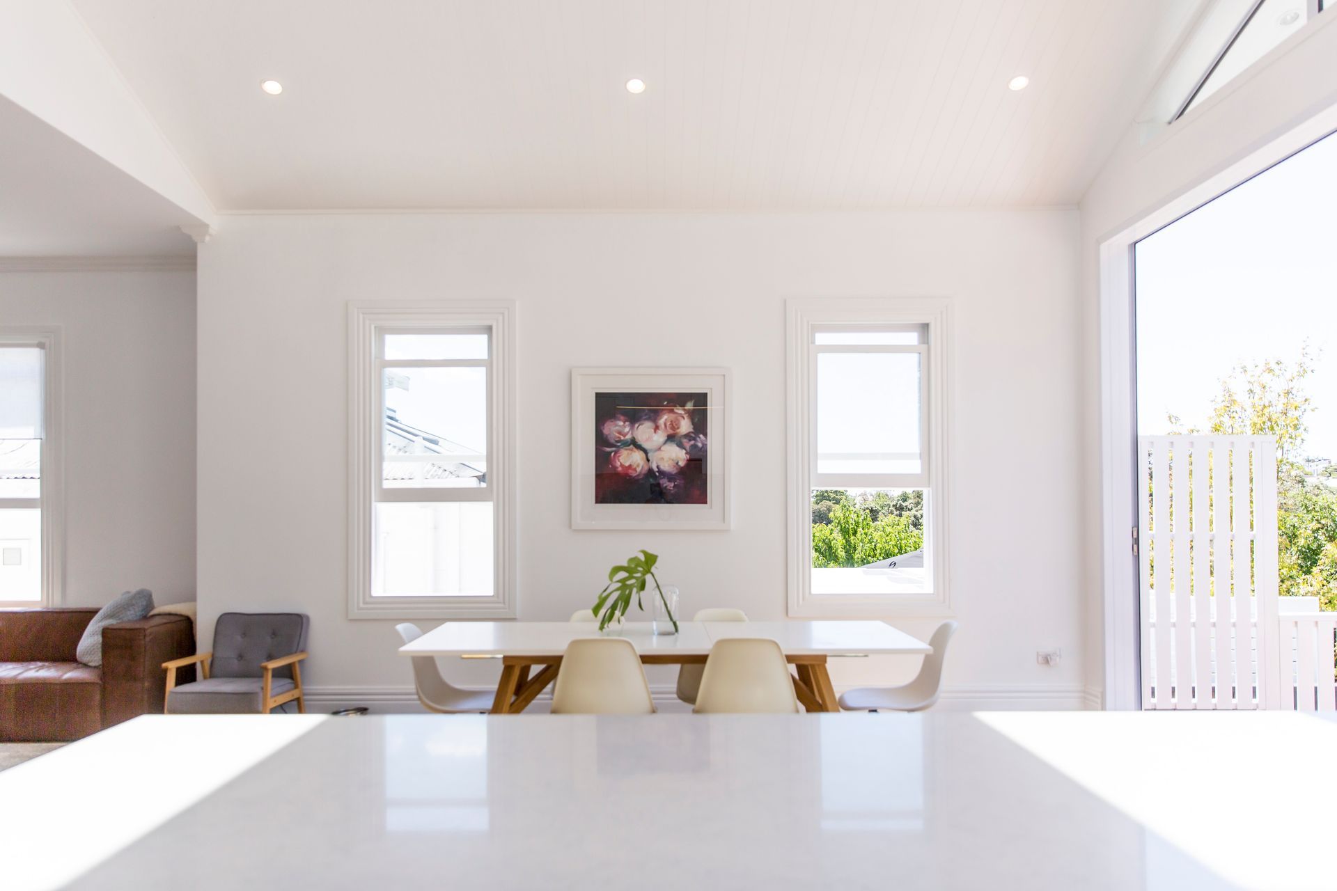 The dining room at Grey Lynn Villa — white dining table, stacking sliders opening to the garden and light pouring in from every direction. Macfie Architecture.