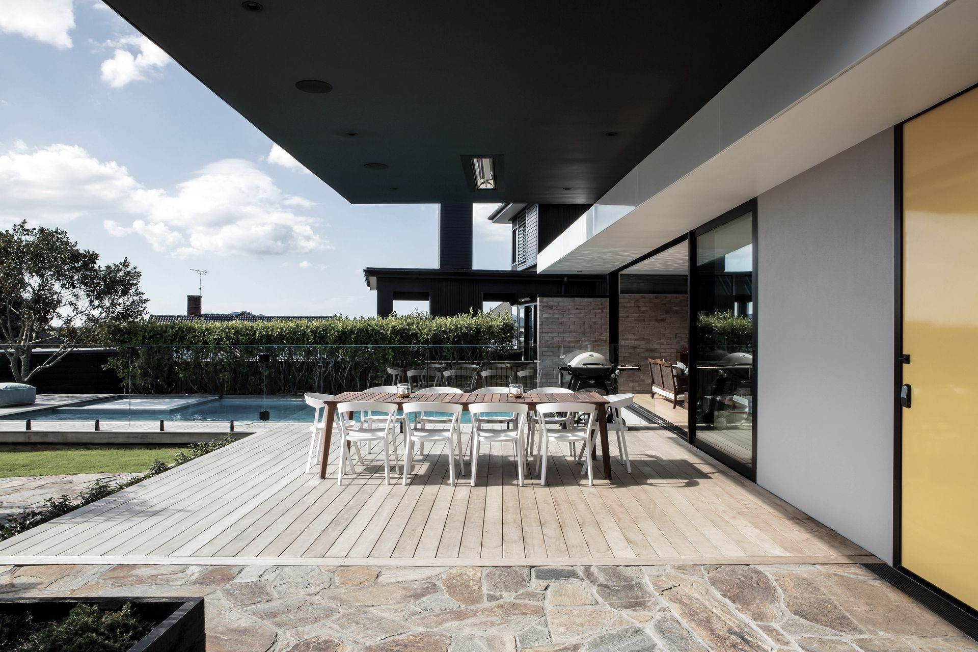 This modernist-inspired home includes bright yellow accents and  crazy paving that runs from the front patio area, seen here, indoors to the entry.