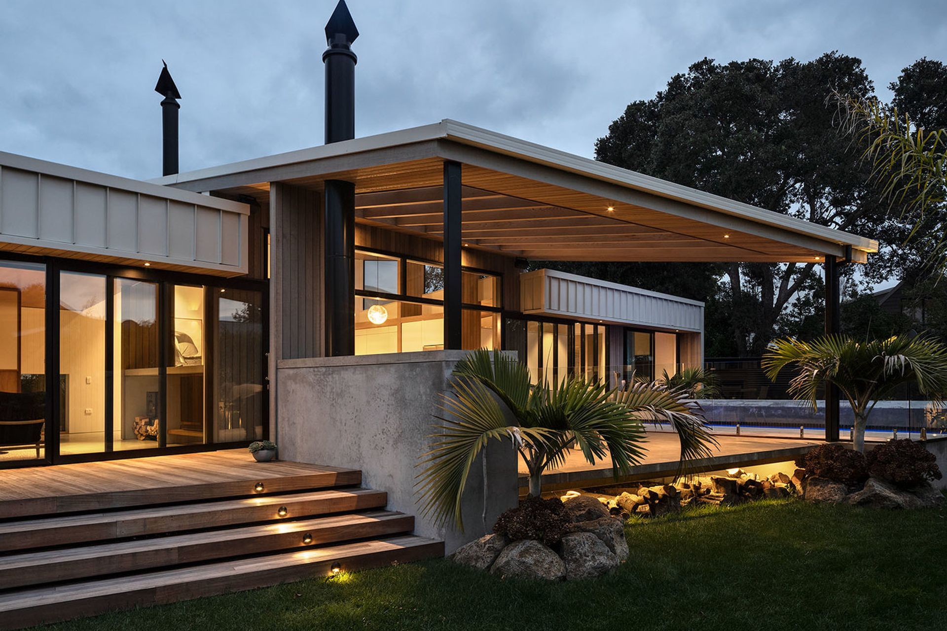 The outdoor living area is sheltered by a sail-like canopy with cedar-panelled soffit and a slatted shade.