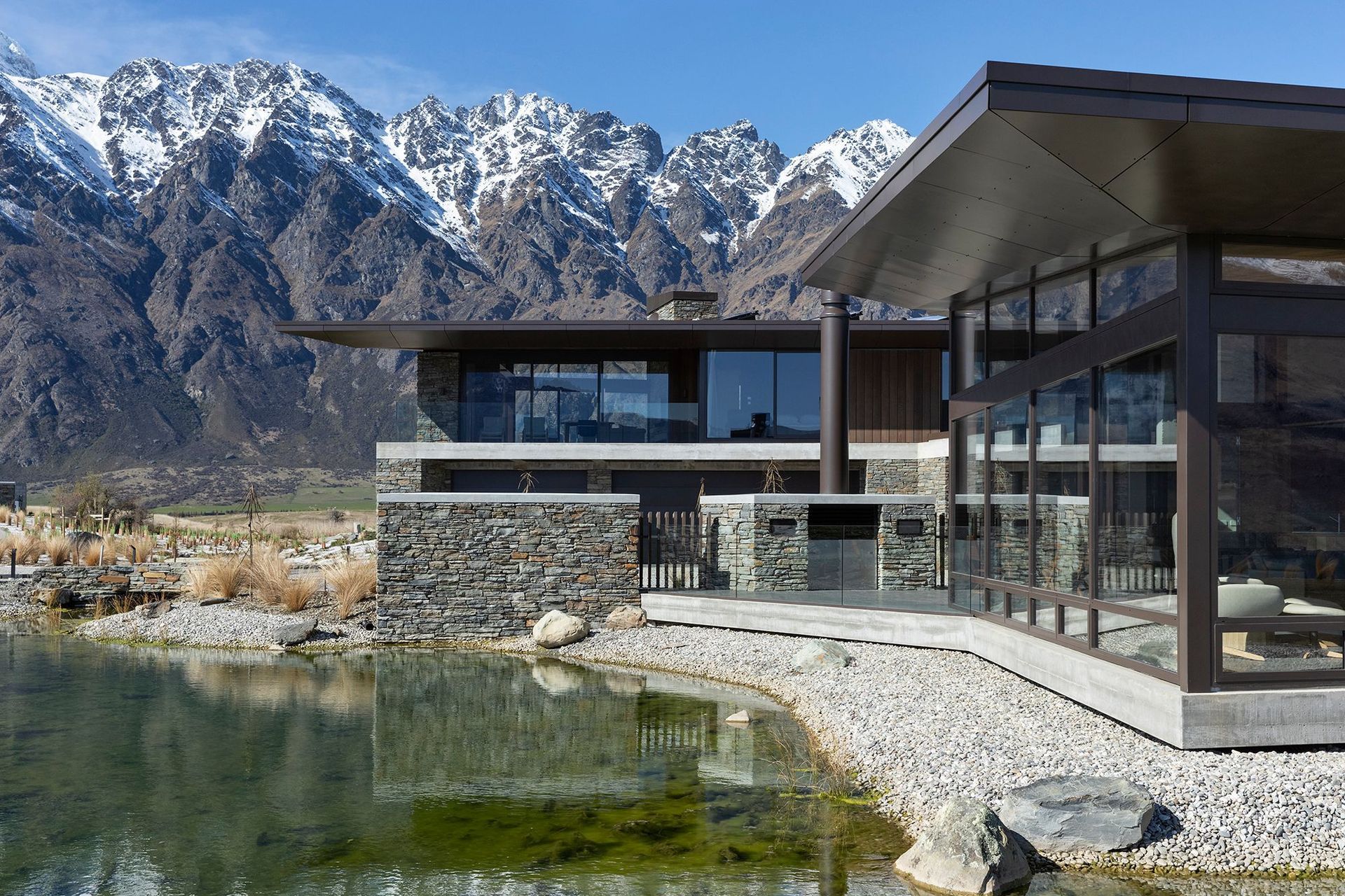 A natural tarn, or waterway, filters down to a manmade reflection pool below the house. A central courtyard with a fireplace is one of the sheltered outdoor areas around the house. SD.