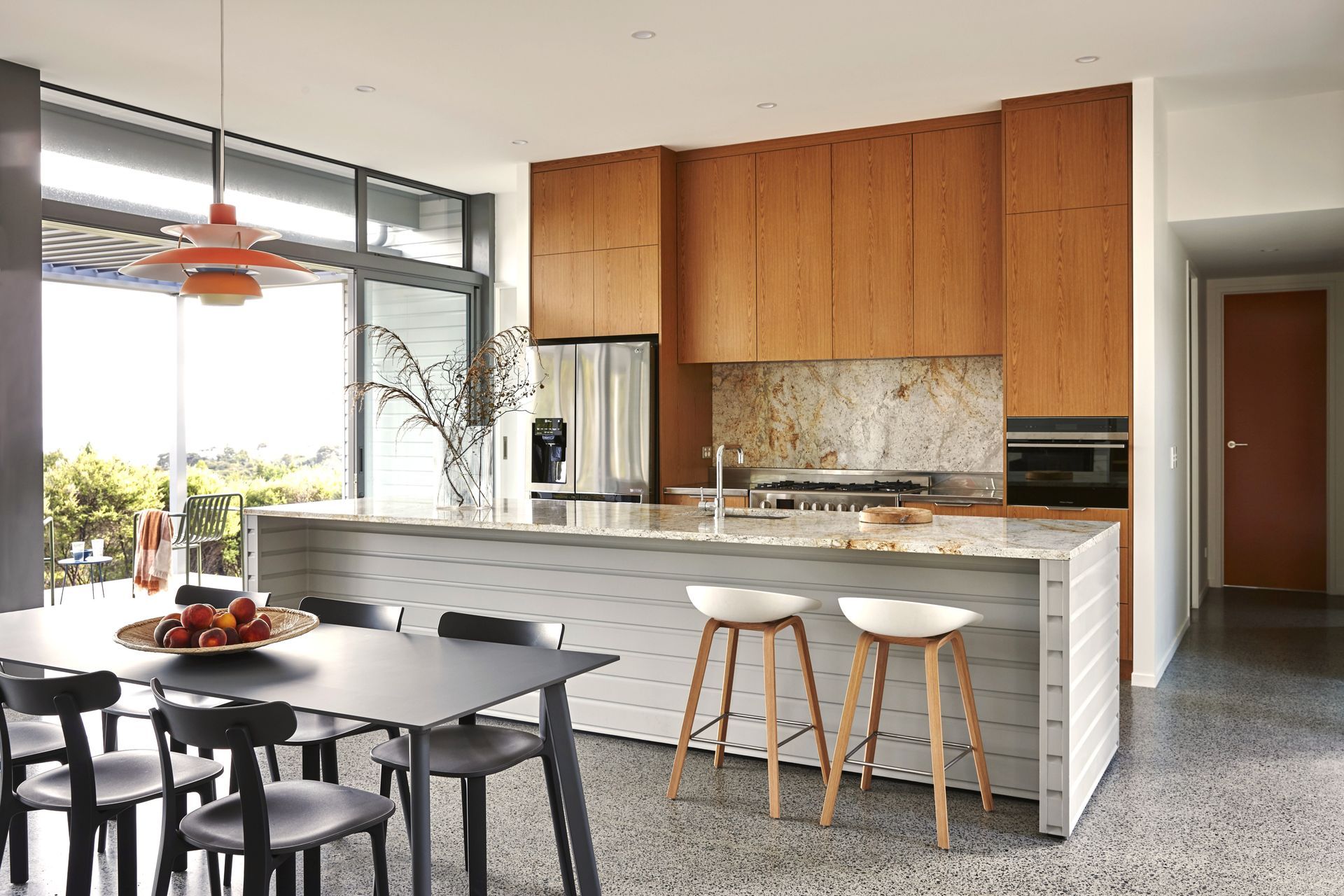 Looking back towards the kitchen, warm oak cabinetry and a granite island create a timeless family kitchen. A generous scullery tucked beyond keeps the main living space beautifully organised.