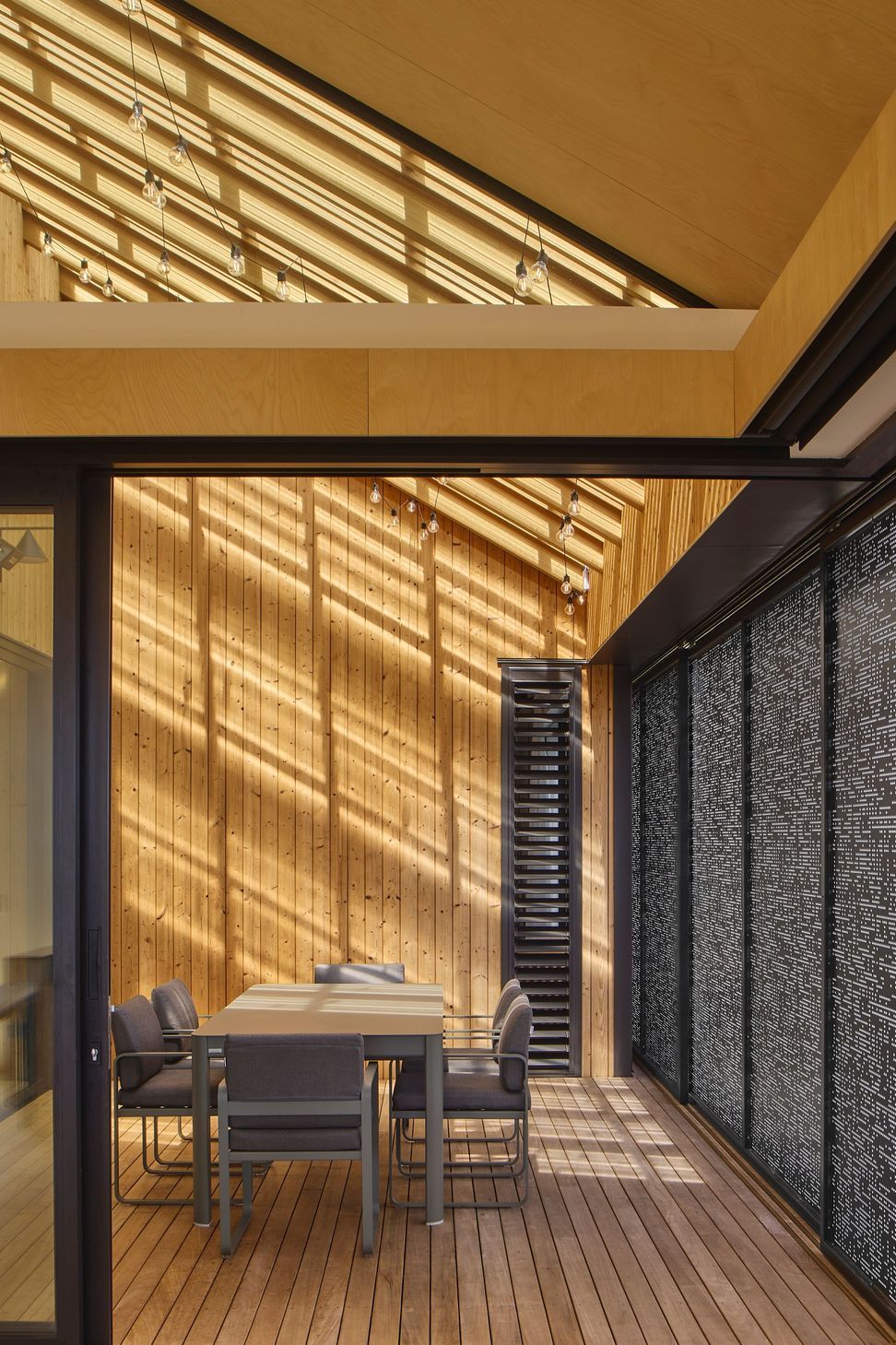 The internal courtyard sits beneath a glazed skillion roof that fills the space with natural light. Timber linings, lush planting and an outdoor dining table create a protected garden room at the centre of the house.