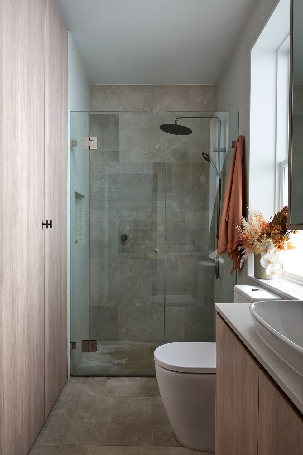 The shared bathroom takes advantage of its location and access to preinstalled services. Sharing footprint, the space underneath the stairs is further utilised as laundry, and storage space, concealed behind seamless joinery accessed through the bathroom.