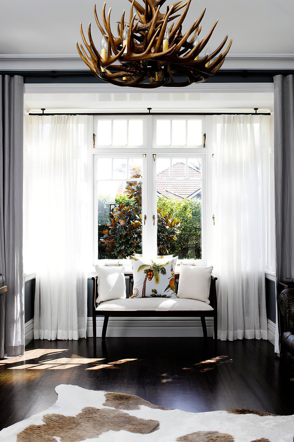 BRITISH COLONIAL STYLE LIVING ROOM - A whimsical window treatment is perfectly paired with the striking elements of this living room.