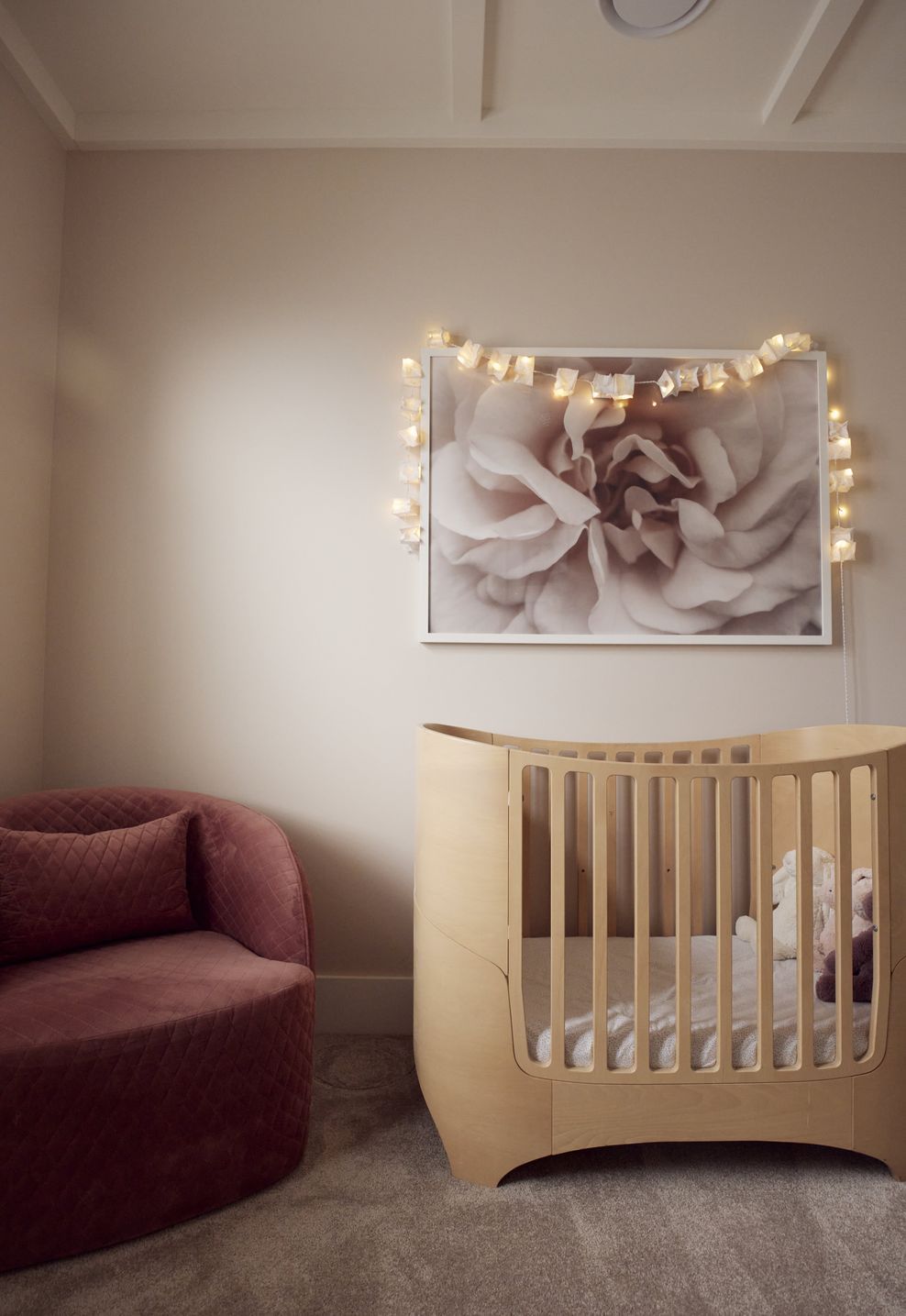 The nursery at Point Chevalier Bungalow — timber cot, dusty pink curved sofa and fairy lights creating a warm and gentle first room. In collaboration with Hannah Warren Interiors.