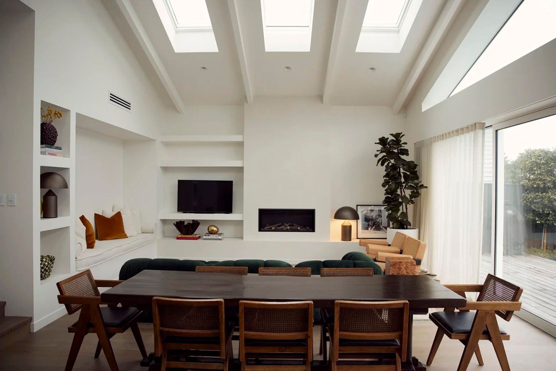 Skylights, exposed rafters, a linear fireplace and built-in window seat — the rear addition at Point Chevalier showing the full cathedral volume in use. In collaboration with Hannah Warren Interiors.