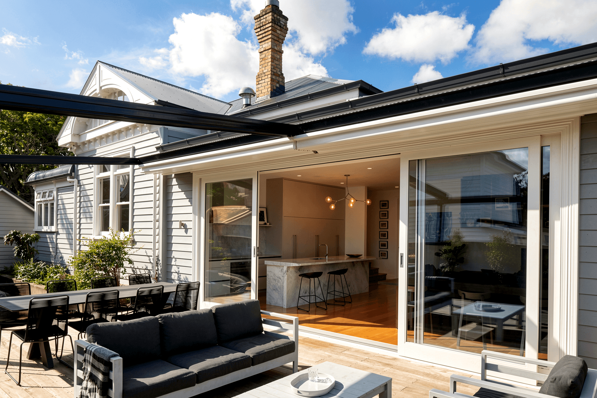 Viewed from the outdoor entertaining area, the contemporary addition opens seamlessly to the deck while maintaining a respectful relationship with the original villa beyond.