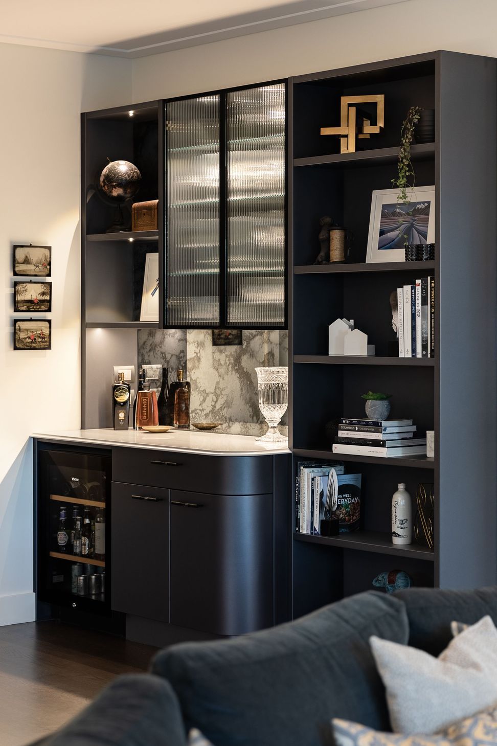 Continuing the elegant shimmering navy palette, the reeded glass, ogee edge and gentle curves, Toni recommended replacing a timber bookcase with a built-in bar and display wall.