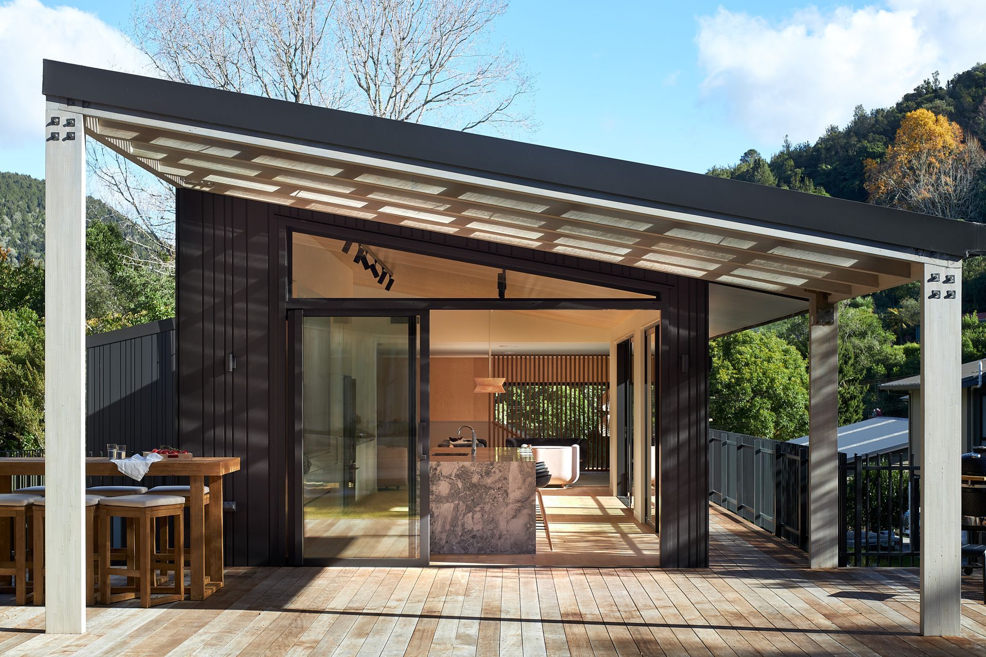 Large sliding doors dissolve the boundary between indoors and out, allowing the open-plan kitchen, dining and living spaces to flow naturally onto the covered deck. The restrained material palette reinforces the home's connection to its lake setting.