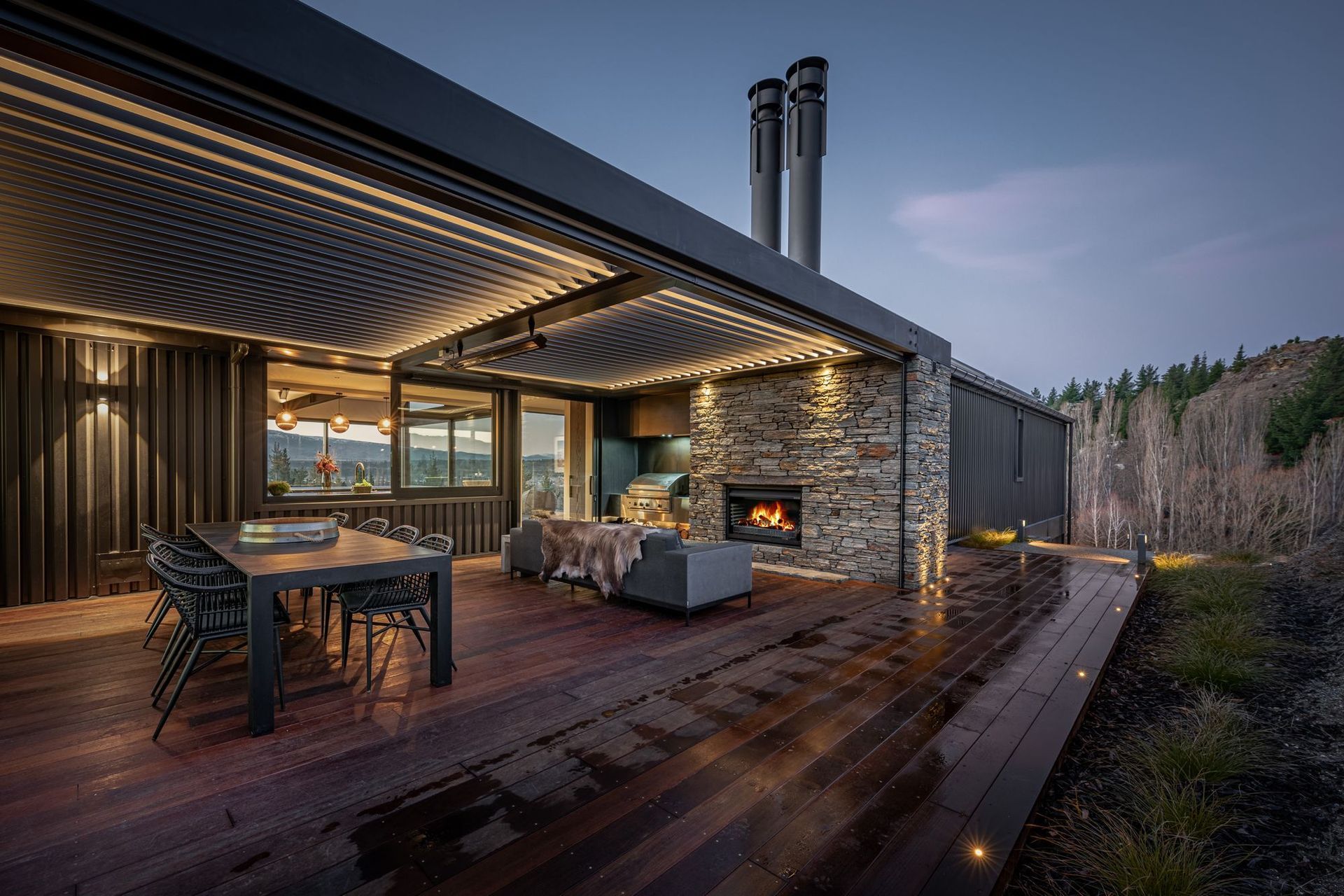 At the rear of the house, adjacent to the kitchen, an external courtyard with schist fireplace and operable louvred roof provide a sheltered space outdoors to enjoy year-round.