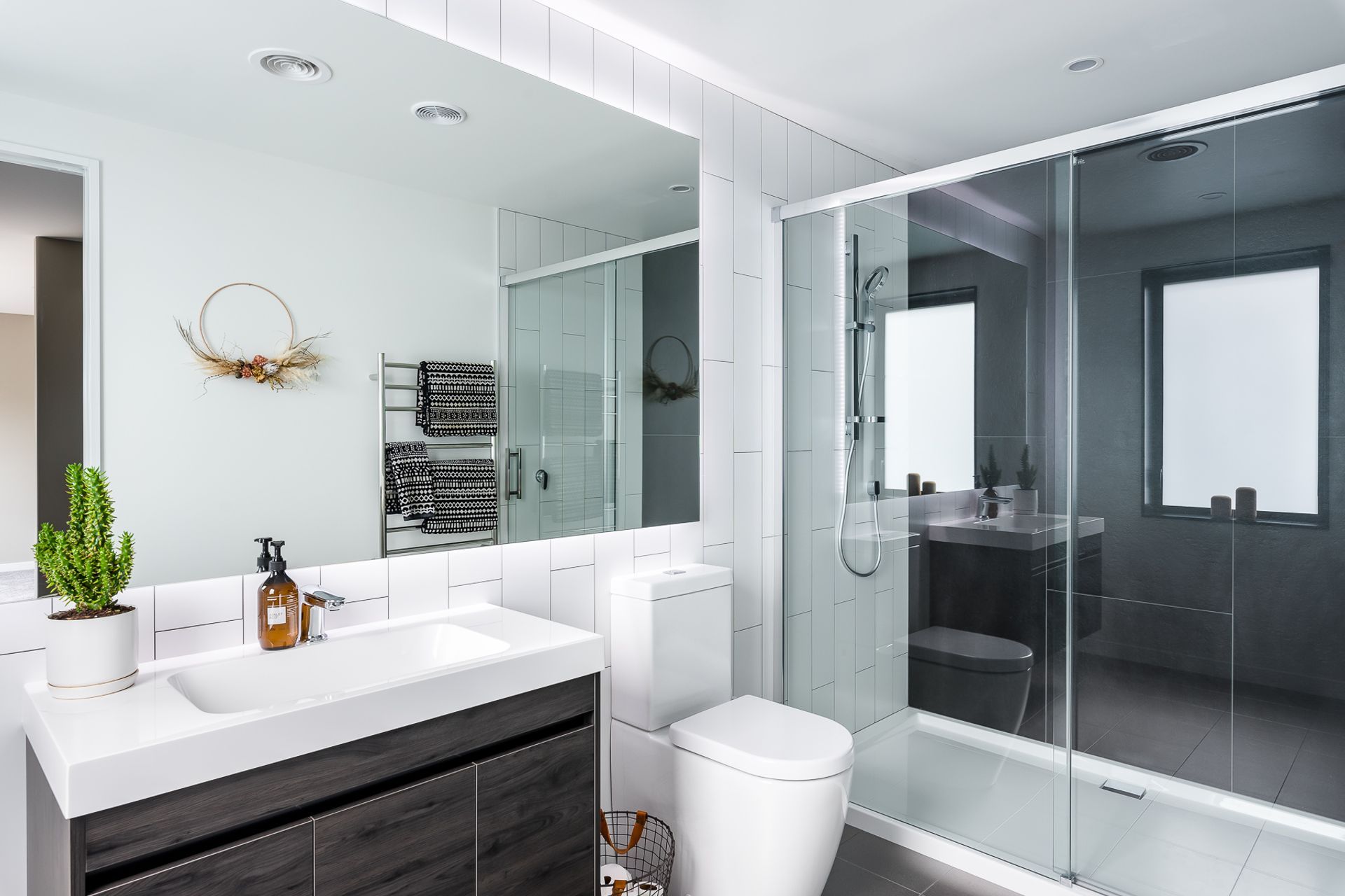 Verticality once again makes an appearance in the main ensuite while the dichromatic colour scheme imparts a very modern feel. The timber-look finish on the vanity references the home's intimate link to its environment.
