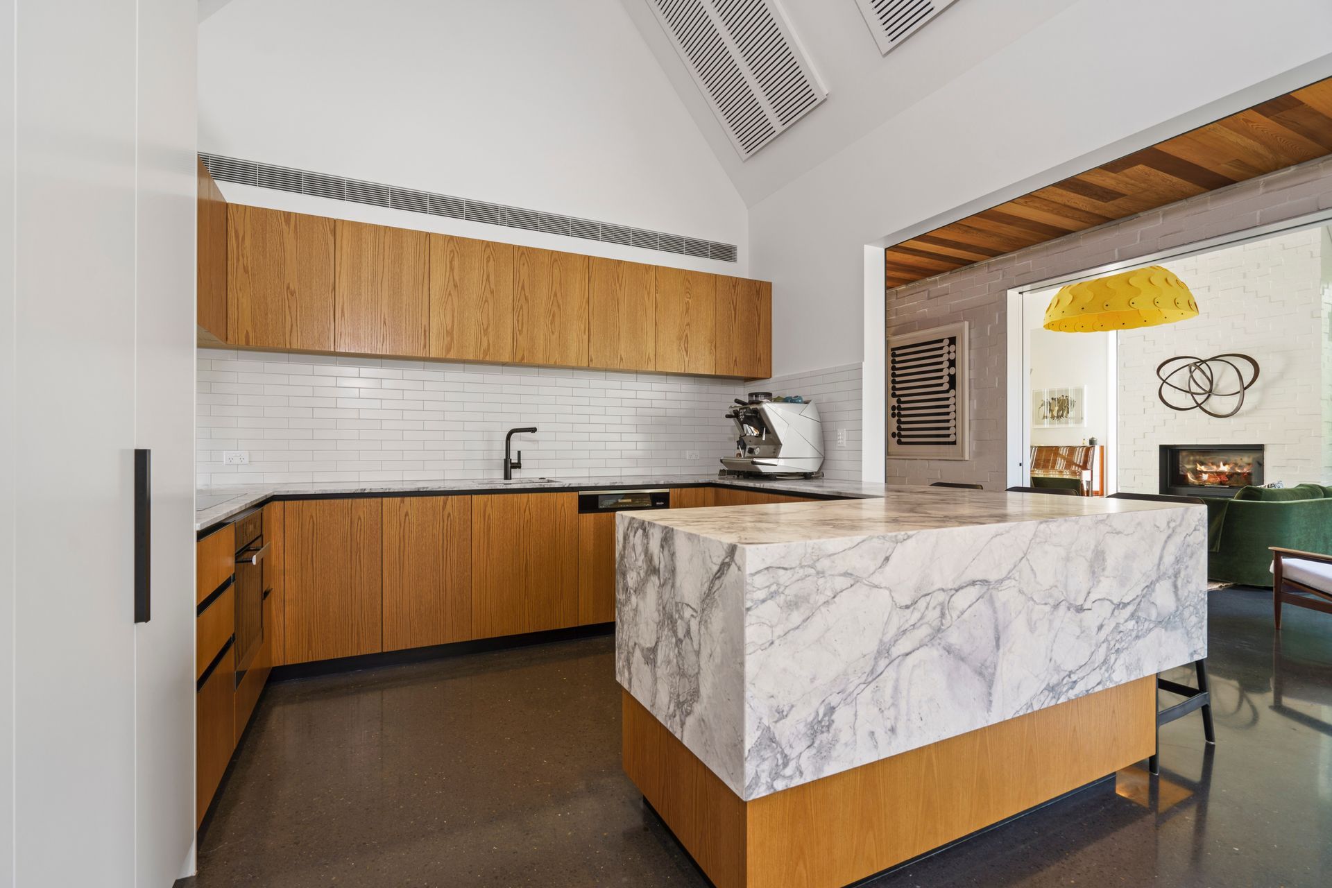 A dramatic peninsula-style island is a bold addition to the kitchen with the cool stone and warm timber complementing each other.