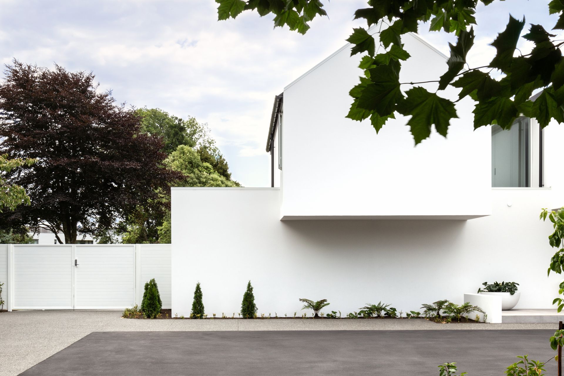 The single tone white plaster finish creates a cohesiveness to the different shapes of the home's form.