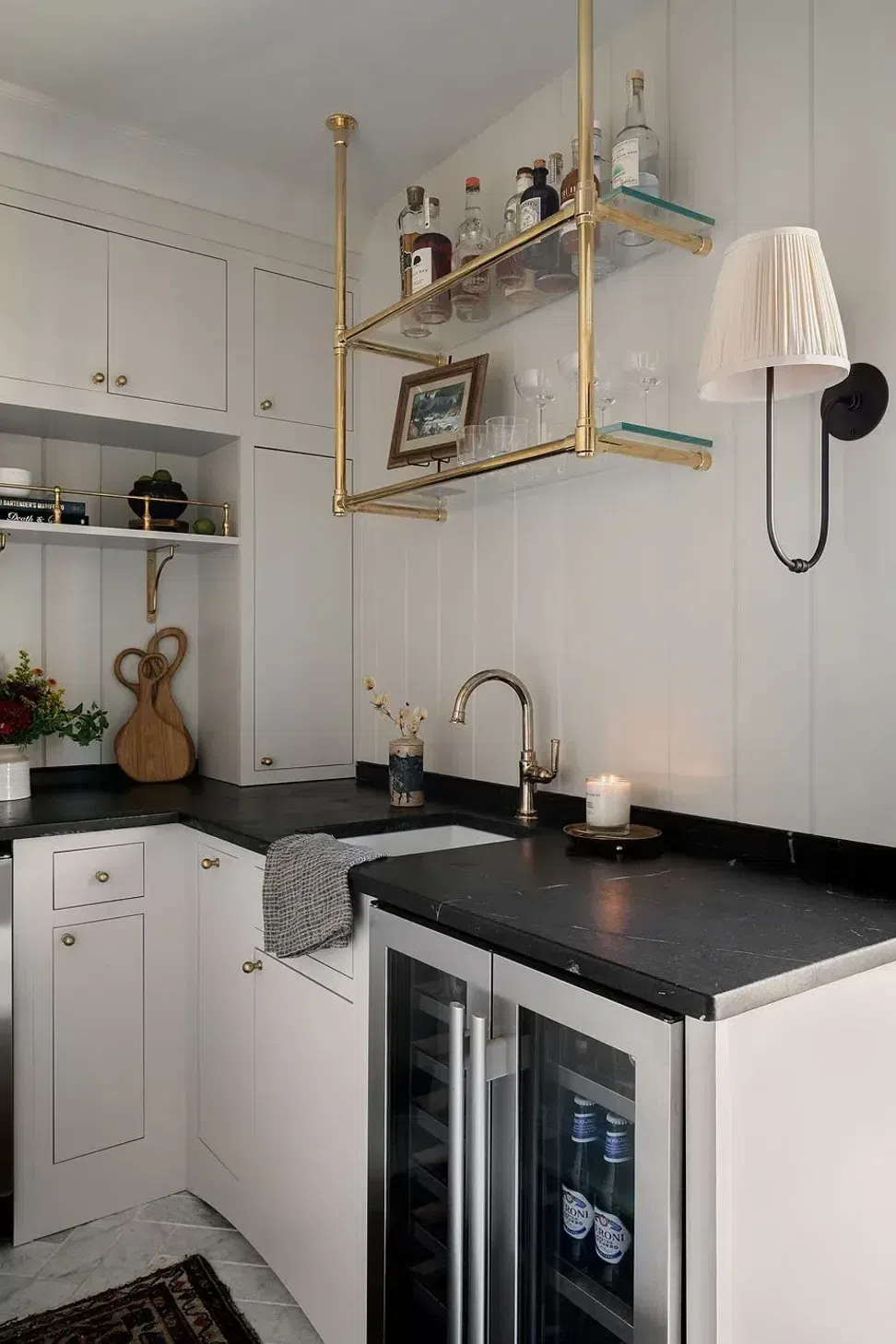 off-white-wood-vertical-shiplap-wall-bar-area-black-stone-countertop-bronze-glass-shelves-sharp-and-grey-interiors.webp