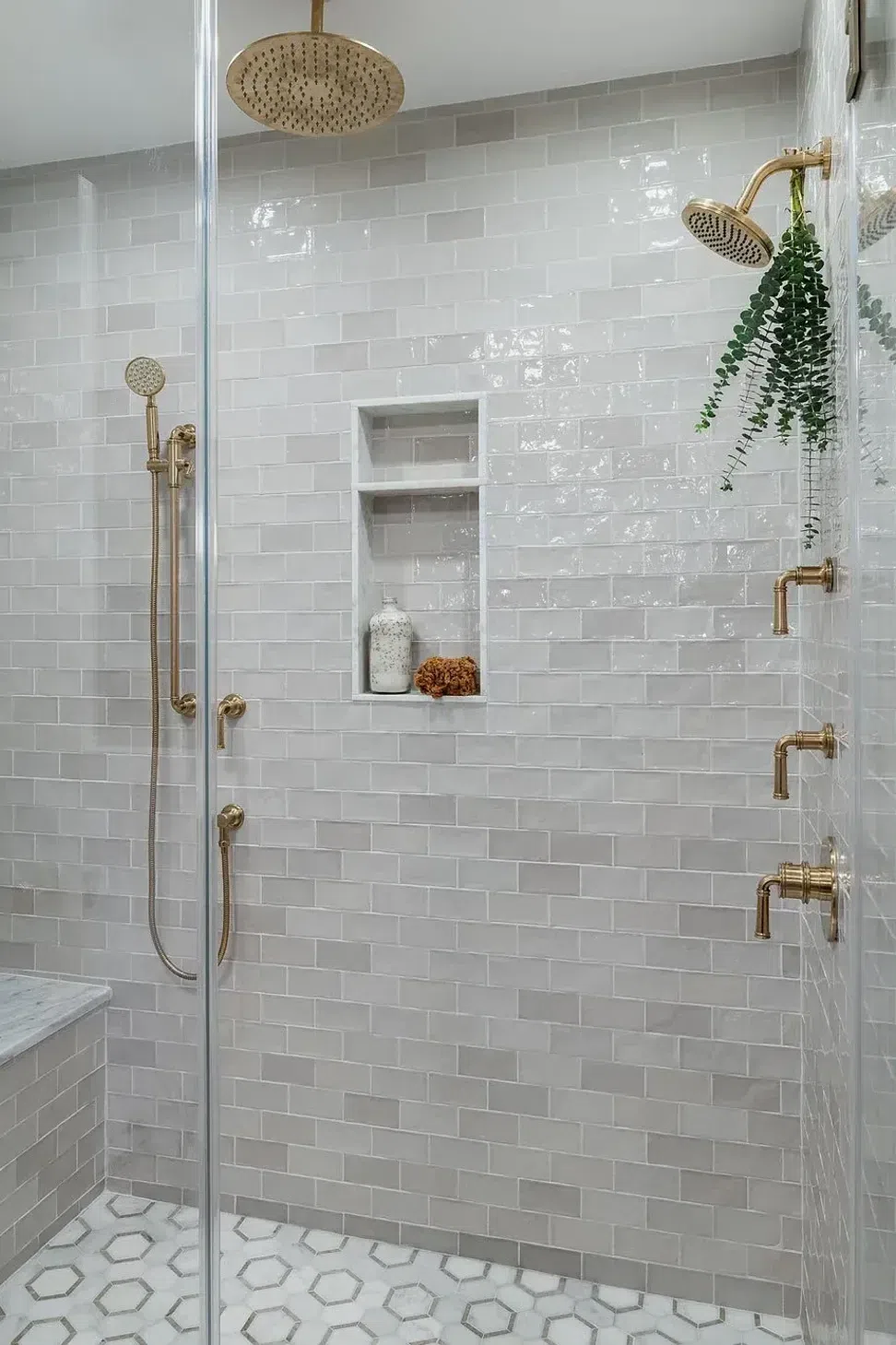 soft-grey-subway-tile-shower-marble-hexagon-tile-floor-bronze-plumbing-sharp-and-grey-interiors.webp