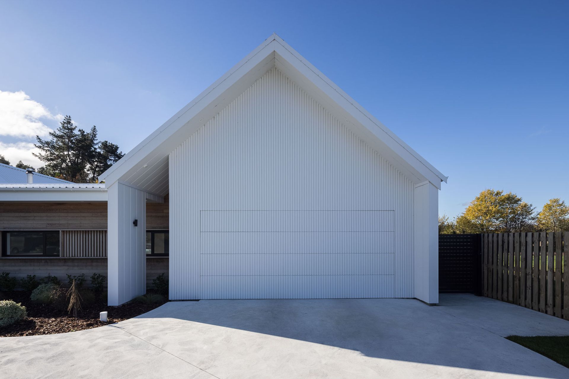 The flush-mounted garage door helps maintain the seamless look of the gable end on the eastern pavilion, which also houses the main bedroom.